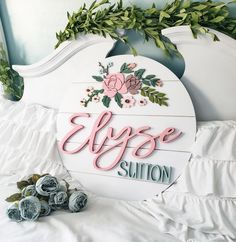 a white bed topped with flowers and greenery next to a sign that says elye solution