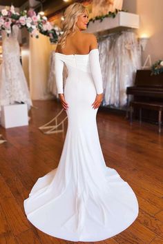 a woman in a white dress standing on a wooden floor with her back turned to the camera