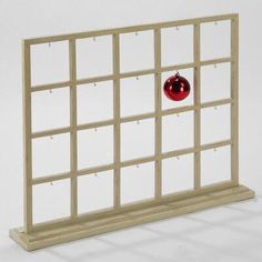 a red ornament sitting on top of a wooden window pane with holes in it