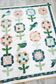 a quilt with flowers on it sitting on top of a wooden floor