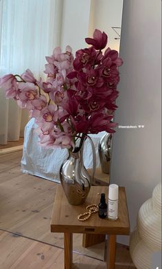 a vase filled with pink flowers sitting on top of a table next to a mirror