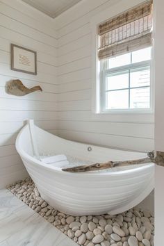 a white bath tub sitting in the middle of a bathroom next to a stone floor