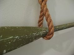 a rope hanging from the side of a boat on a wooden pole next to a white wall