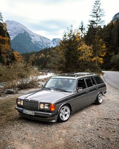 a car parked on the side of a road in front of some trees and mountains