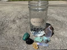 a jar filled with lots of stones sitting on top of a cement ground