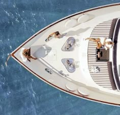 two people sitting on the bow of a boat in the water, looking down at the deck