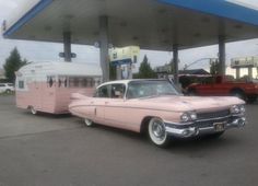 an old pink car parked in front of a gas station