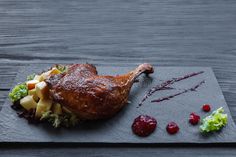 a piece of meat with cranberry sauce and lettuce on a slate board