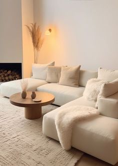 a living room with a large white couch and coffee table in front of a fire place