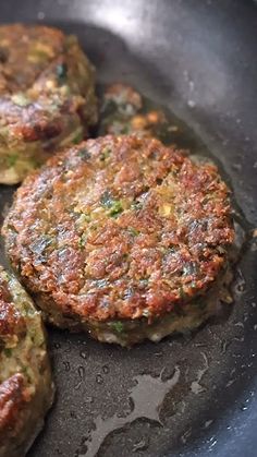 three hamburger patties cooking in a frying pan