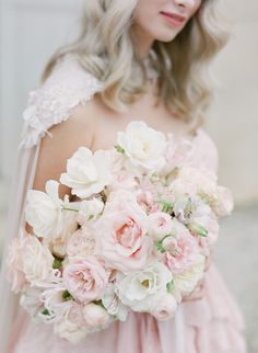 a woman in a pink dress holding a bouquet of white and pink flowers on her shoulder