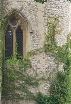 an old stone building with ivy growing on it's side and a window in the middle