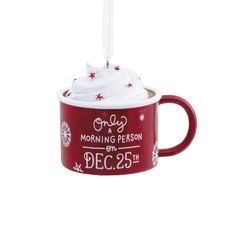 a red coffee mug ornament with white frosting and stars on the top