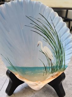 a white bird sitting on top of a glass bowl with water and grass in it