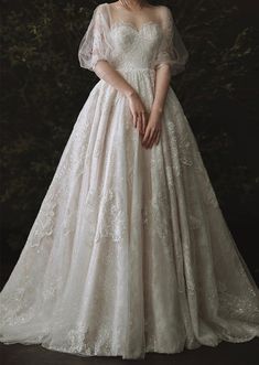 a woman in a white wedding dress standing against a dark background with her hands on her hips