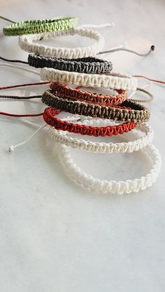 five different colored bracelets on a white counter top with strings attached to each one