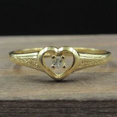 a gold ring with a heart shaped diamond on it's center and two smaller hearts in the middle