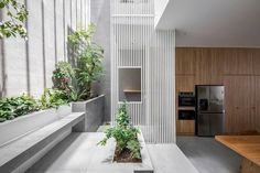 an indoor kitchen and living area with plants in the center, along with stairs leading up to the upper floor