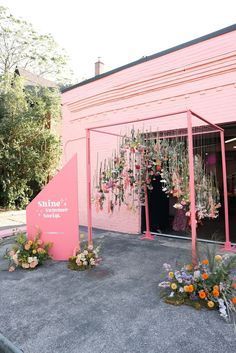 a pink building with flowers hanging from it's sides and an awning over the entrance