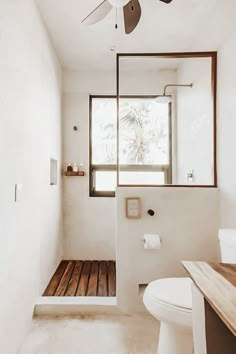 a bathroom with a ceiling fan and wooden flooring