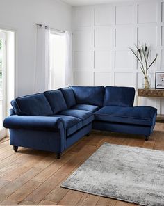 a living room with a blue sectional couch and rug on the wooden floor next to a window