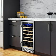 a wine cooler in the middle of a kitchen with marble counter tops and gray cabinets