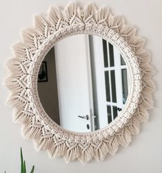 a round mirror hanging on the wall next to a potted plant