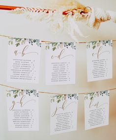 wedding seating cards hanging from a string with leaves and flowers on them for guests to sign