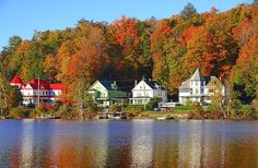 houses on the shore of a lake surrounded by trees with fall foliage in the background