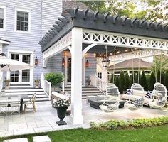 an outdoor living area with white furniture and umbrellas on the patio, next to a blue house