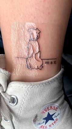 a small tattoo on the ankle of a woman's leg that has a dog sitting on it