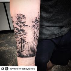 a man's arm with a forest scene tattoo on the left side of his arm