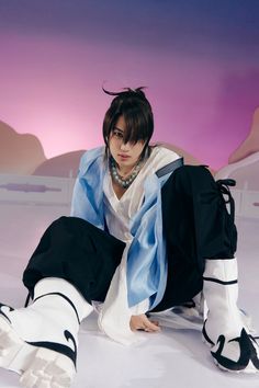 a woman is sitting on the ground with her legs crossed and wearing black and white clothes