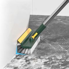 a broom cleaning the floor in front of a white wall with black and yellow accents