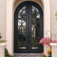 a black double door with two sidelights and flowers on the steps in front of it