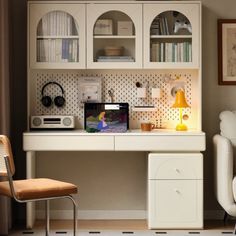 a white desk with a laptop on top of it next to a chair and bookcase