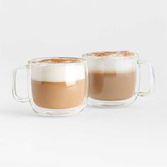 two mugs filled with coffee sitting next to each other