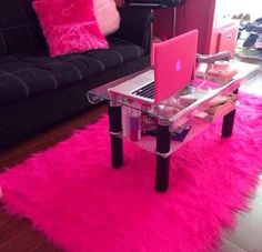 a living room with a black couch and pink rug on the floor next to a laptop computer