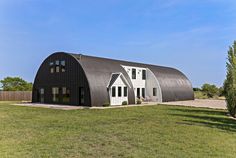 a large metal building sitting on top of a lush green field