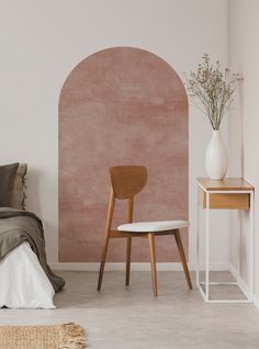 a bedroom with a bed, table and chair next to a wall painted in pink