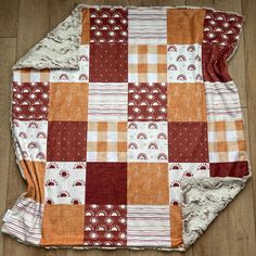 an orange and white patchwork blanket laying on top of a wooden floor