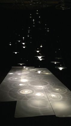 an illuminated dance floor in the middle of a dark room with lights shining down on it