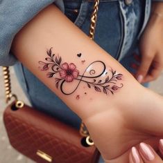 a woman's arm with a tattoo on it that has flowers and hearts in the middle