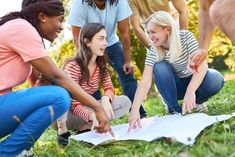 group of young people sitting on the grass and looking at something in front of them