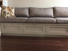 a gray couch sitting on top of a hard wood floor next to a white wall