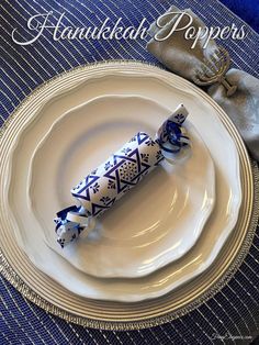 a white plate topped with a decorative blue and white napkin roll on top of it