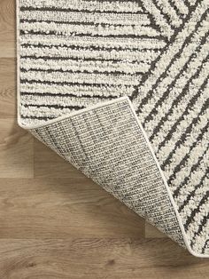 an area rug on top of a wooden floor with a gray and white striped design