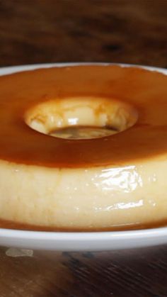 a white plate topped with a donut covered in caramel sauce on top of a wooden table