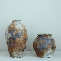 two vases sitting next to each other on a white counter top in front of a wall