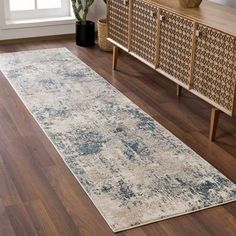 a large area rug in the middle of a living room with wooden furniture and potted plants